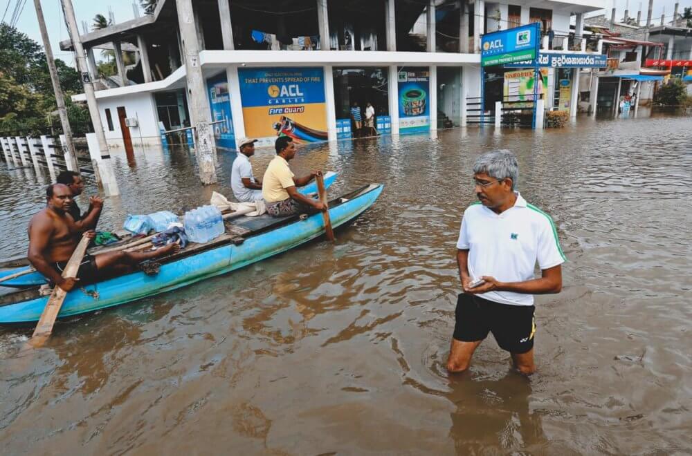 A group of Sri Lankan men use a boat as a mode of transportation as another man walks across the southern expressway at Godagama, Matara southern part of Sri Lanka on 30 Tuesday May 2017